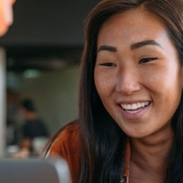 a woman smiling while working on laptop